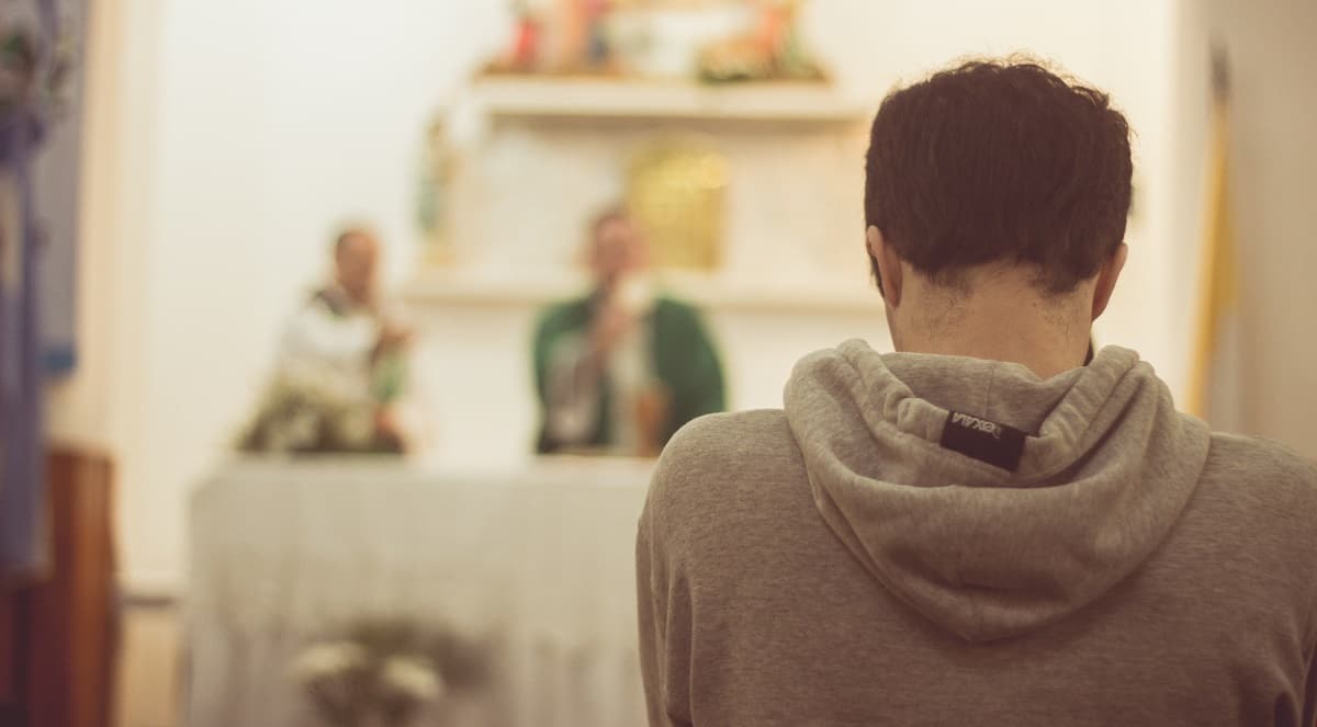 Un joven concentrado en misa, ante el altar