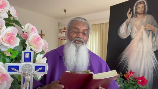 El sacerdote James Manjackal, con flores, la Biblia y el cuadro de la Divina Misericordia