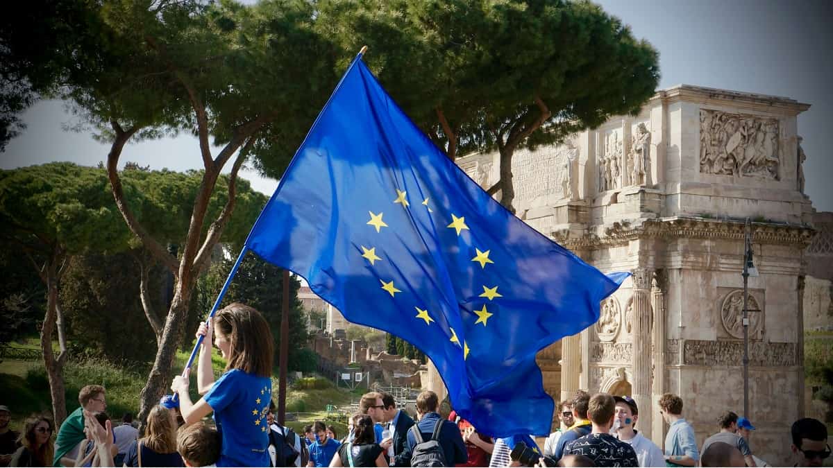 Una joven con la bandera europea en Roma, ante un Arco de triunfo romano