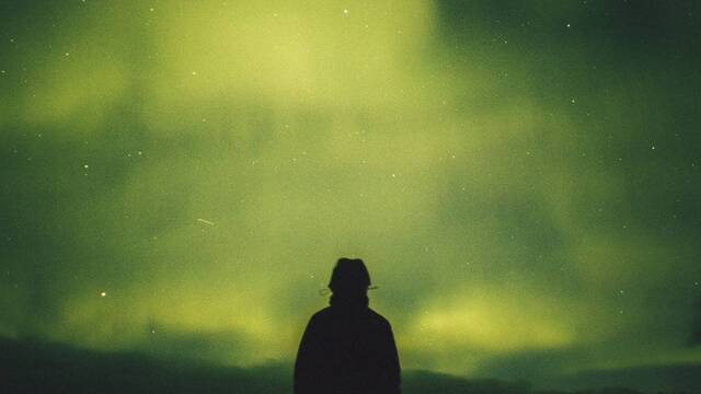 Sombra de un hombre contemplando la aurora boreal.