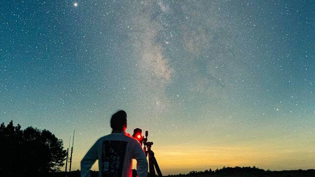 Un hombre mira el cielo con un telescopio.