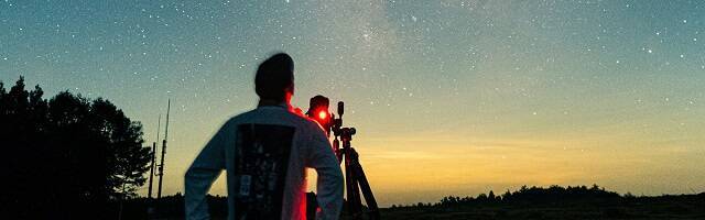 Un hombre con telescopio en el campo mira estrellas, foto de Kazuend en Unsplash