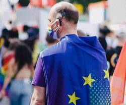 Un hombre con la bandera europea y colores arcoiris, foto de Christian Lue en Unsplash