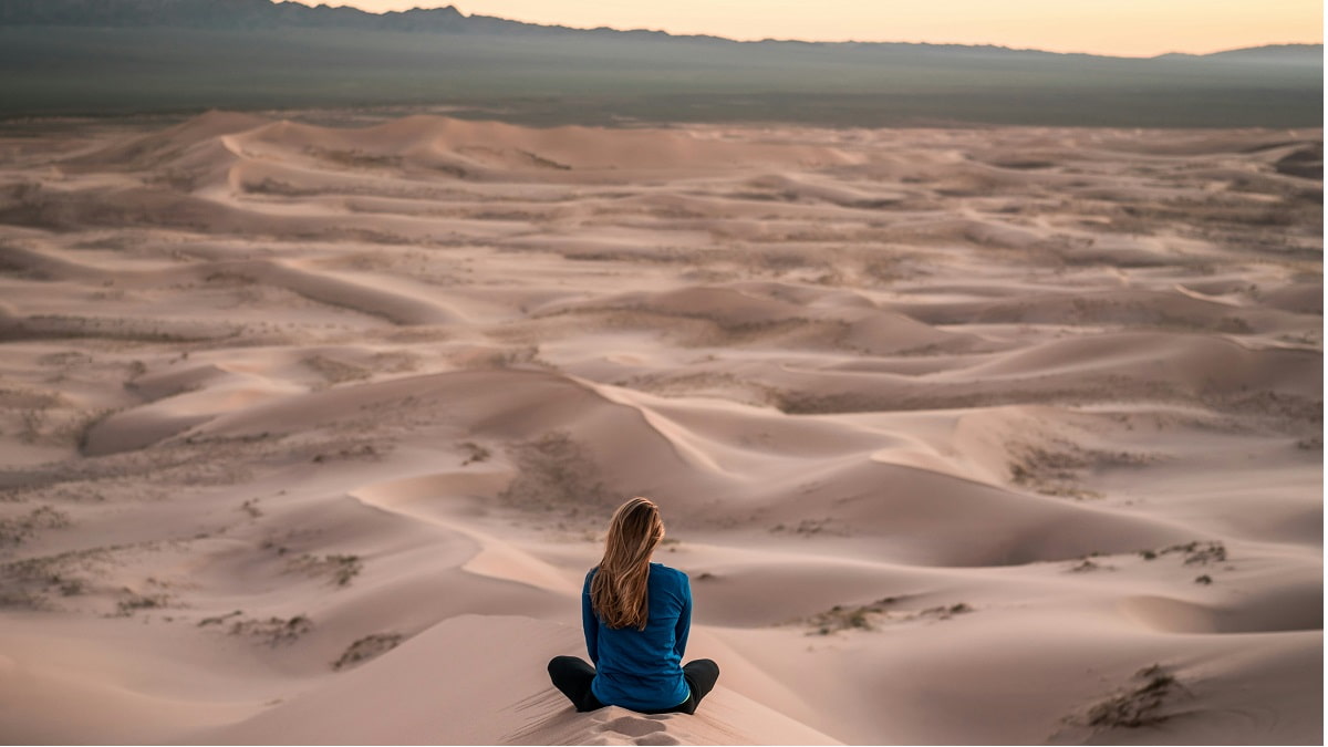 Una chica chica medita en el desierto con dunas, foto de Patrick Schneider para Unsplash