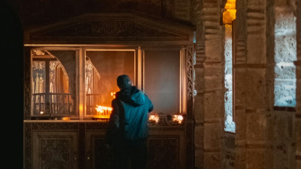 Un hombre enciende unas velas en una iglesia.