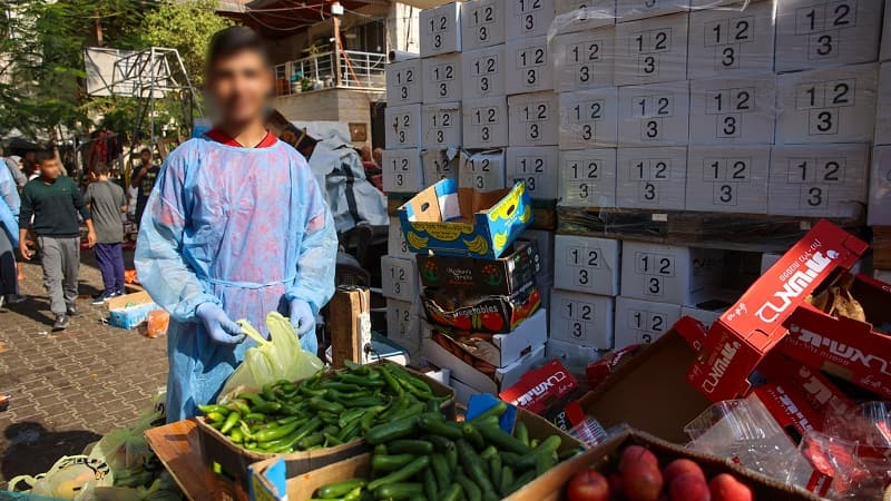 Un muchacho de la parroquia de Gaza ayuda a preparar los lotes de fruta y verdura que la parroquia reparten en la zona