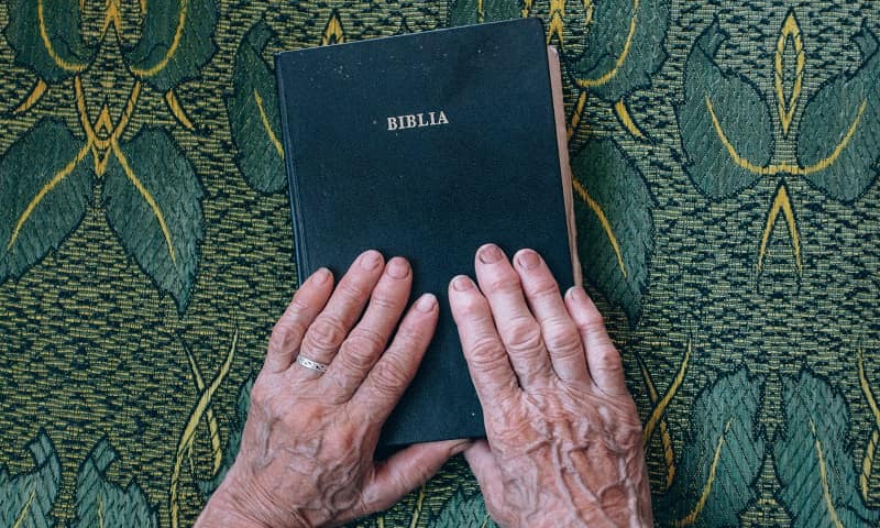 Unas manos sobre la Biblia, en actitud esperanzada, foto de Raul Petri en Unsplash