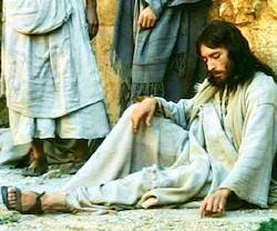 Jesús (Robert Powell) escribe tranquilamente en el suelo en la escena de la lapidación de la adúltera en 'Jesús de Nazaret' de Franco Zeffirelli (1977).