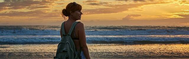 Una mujer en verano contempla la puesta de sol en la playa en Conil de la Frontera