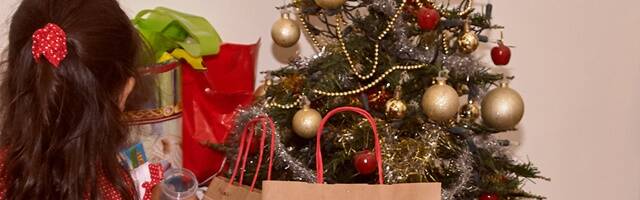 Niña poniendo cosas en el árbol de Navidad.