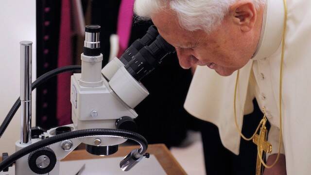 Benedicto XVI mira por un microscopio.
