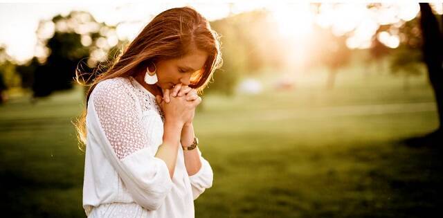 Una mujer en oración, en un campo luminoso, símbolo de esperanza