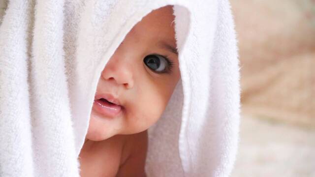 Un bebé con una toalla en la cabeza.