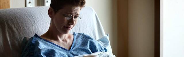 Enferma en la cama de un hospital con cara de tristeza.