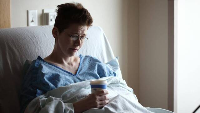 Enferma en la cama de un hospital con cara de tristeza.