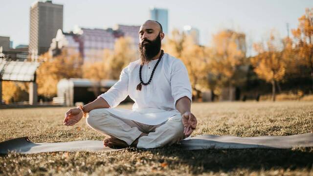 Hombre con aspecto de gurú, en posición de yoga.