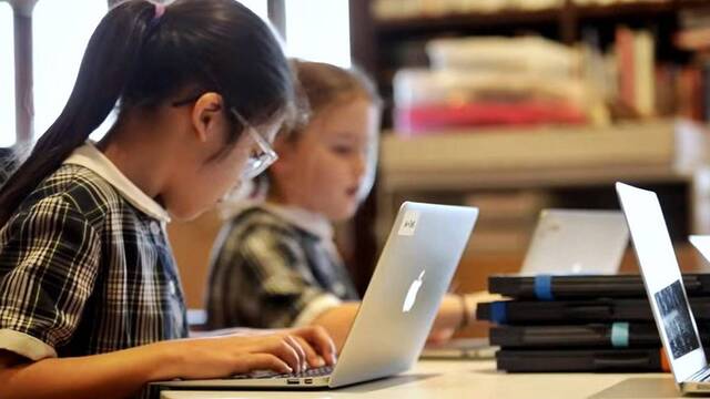 Dos niñas trabajan con un ordenador en la escuela.