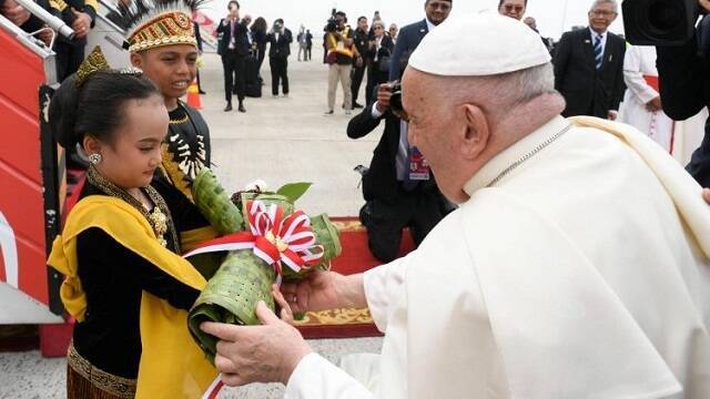 Unos niños con trajes típicos indonesios entregan flores al Papa Francisco a su llegada al aeropuerto de Yakarta