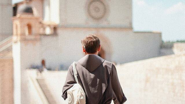 Un joven monje ante una iglesia en Asís