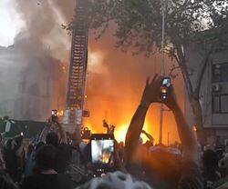 Los manifestantes de extrema izquierda celebran la caída de la torre de la iglesia de la Asunción, en Santiago, que previamente habían quemado.