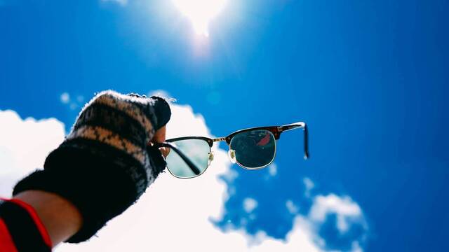 Una mano sostiene unas gafas para mirar el cielo.