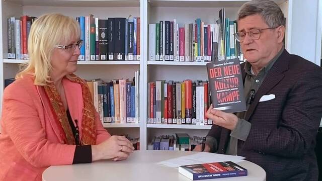 Susanne Schrötter, entrevistada por Roland Tichy, que muestra su libro.