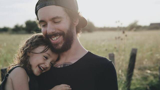 Una niña sonríe en brazos de su padre.