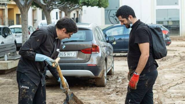 Un sacerdote joven, pala en mano, ayuda en las tareas de limpieza en Valencia.