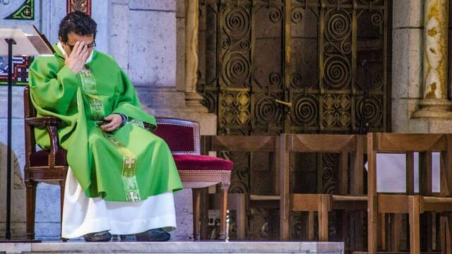 Un sacerdote sentado durante la misa.