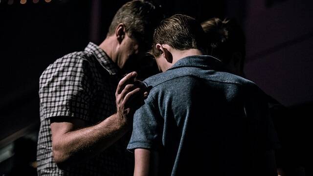 Unos hombres oran por un joven - todos los cristianos pueden hacer oración de intercesión - foto Jack Sharp