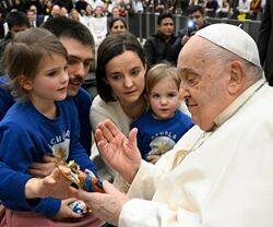 Francisco bendice una imagen del Niño Jesús al ser saludado por una familia presente en la audiencia. Foto: Vatican Media.