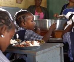 Niñas en un comedor escolar en Haití, con cocineras